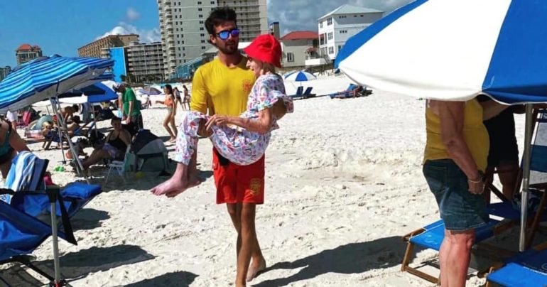 lifeguards carry elderly woman to beach