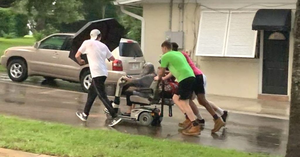 Four Young Men Push An Elderly Woman In Broken Scooter In Pouring Rain ...